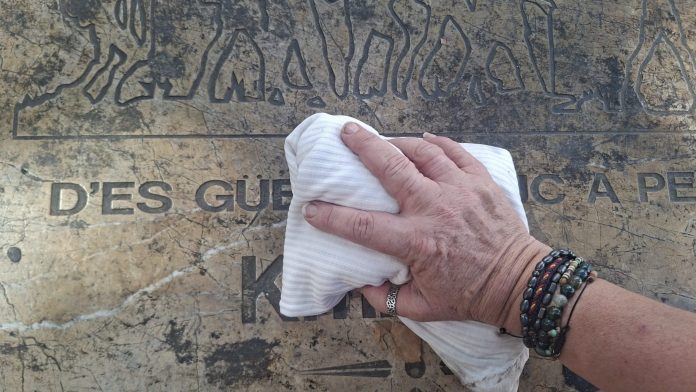 Vecinos de Pere Garau limpian la placa del Kilómetro Cero de la ruta Des Güell a Lluc a Peu para denunciar la suciedad del barrio